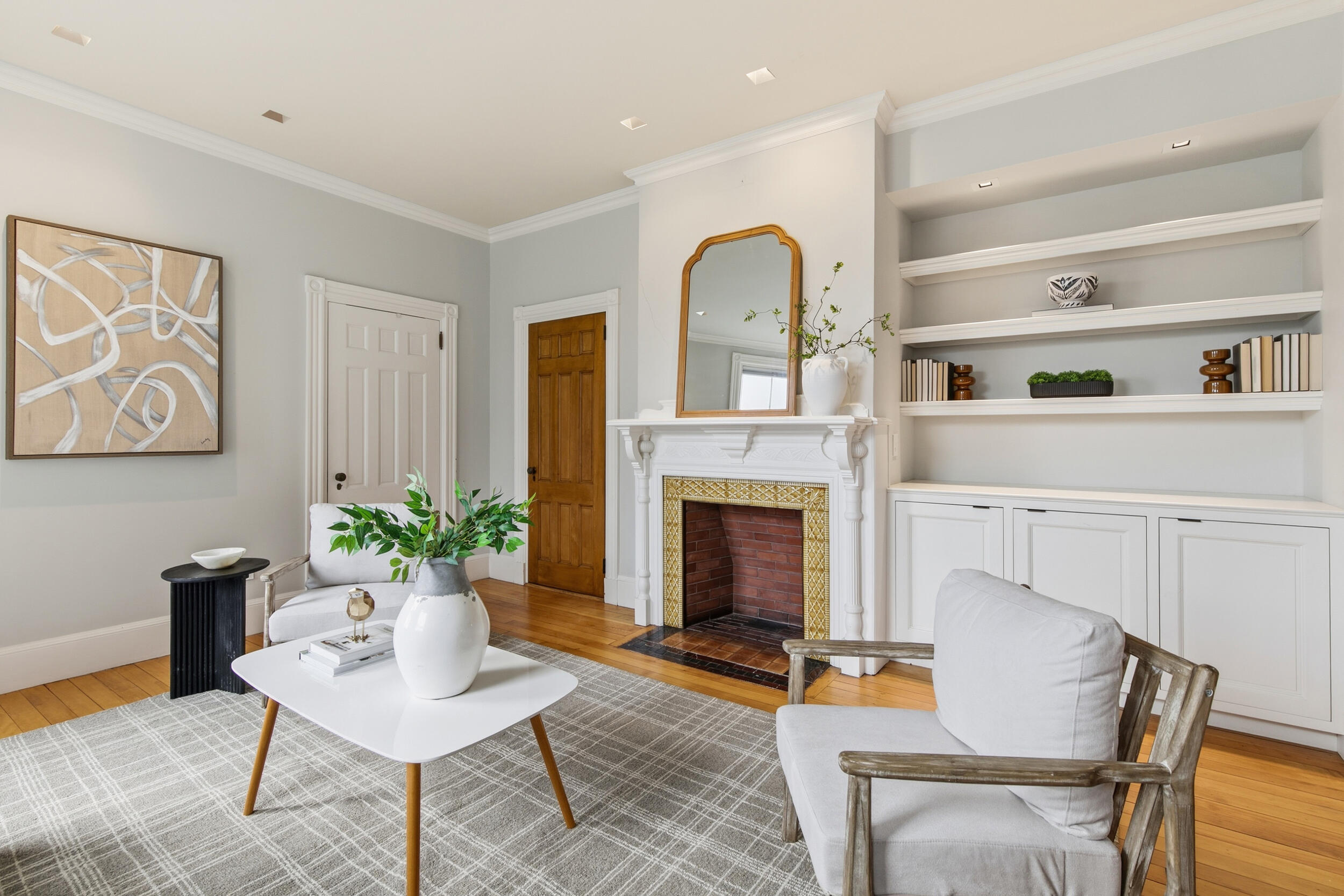Living room with a tiled fireplace, built-in shelves, and hardwood floors.