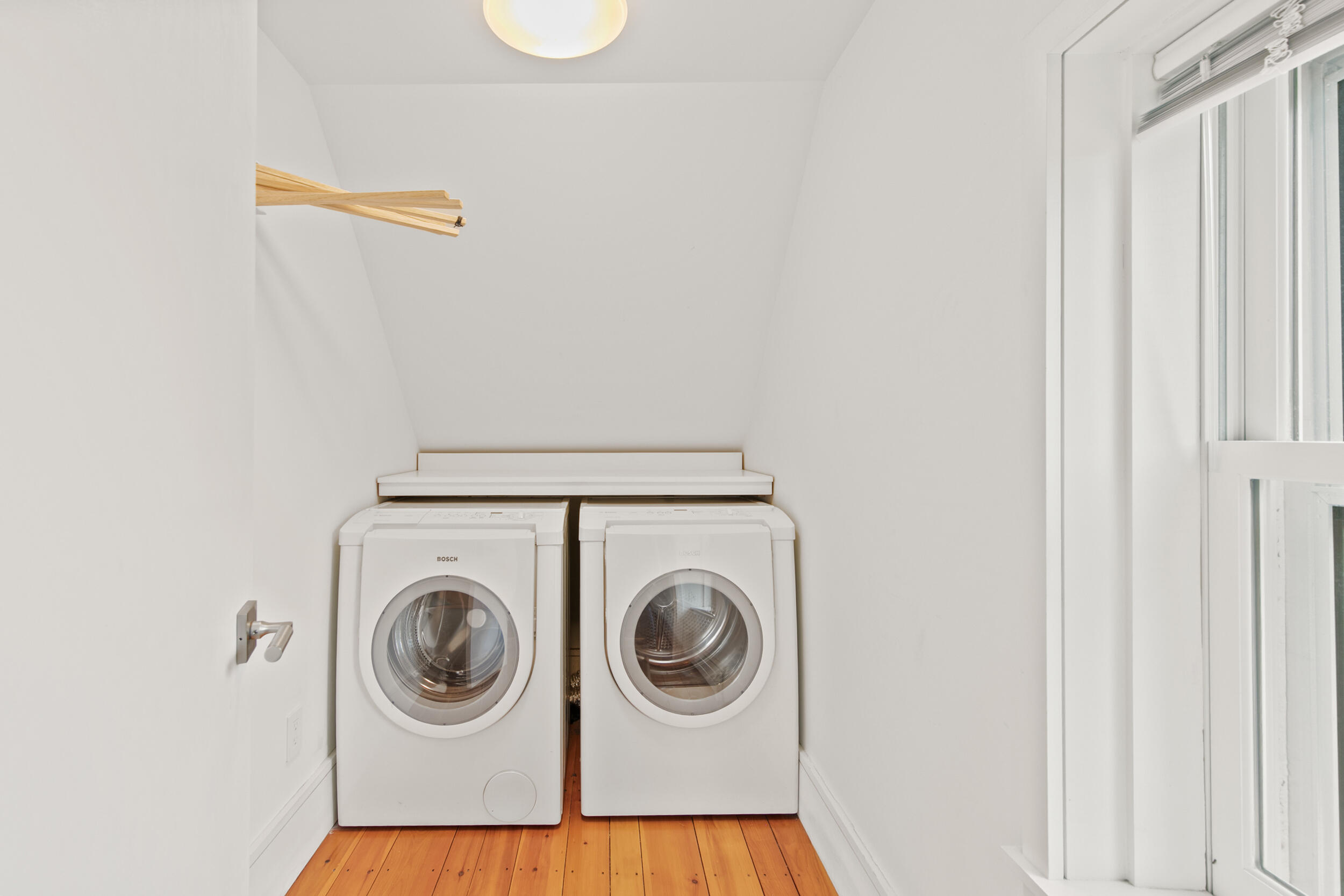 Laundry room with side-by-side front-loading washer and dryer beneath a sloped ceiling.