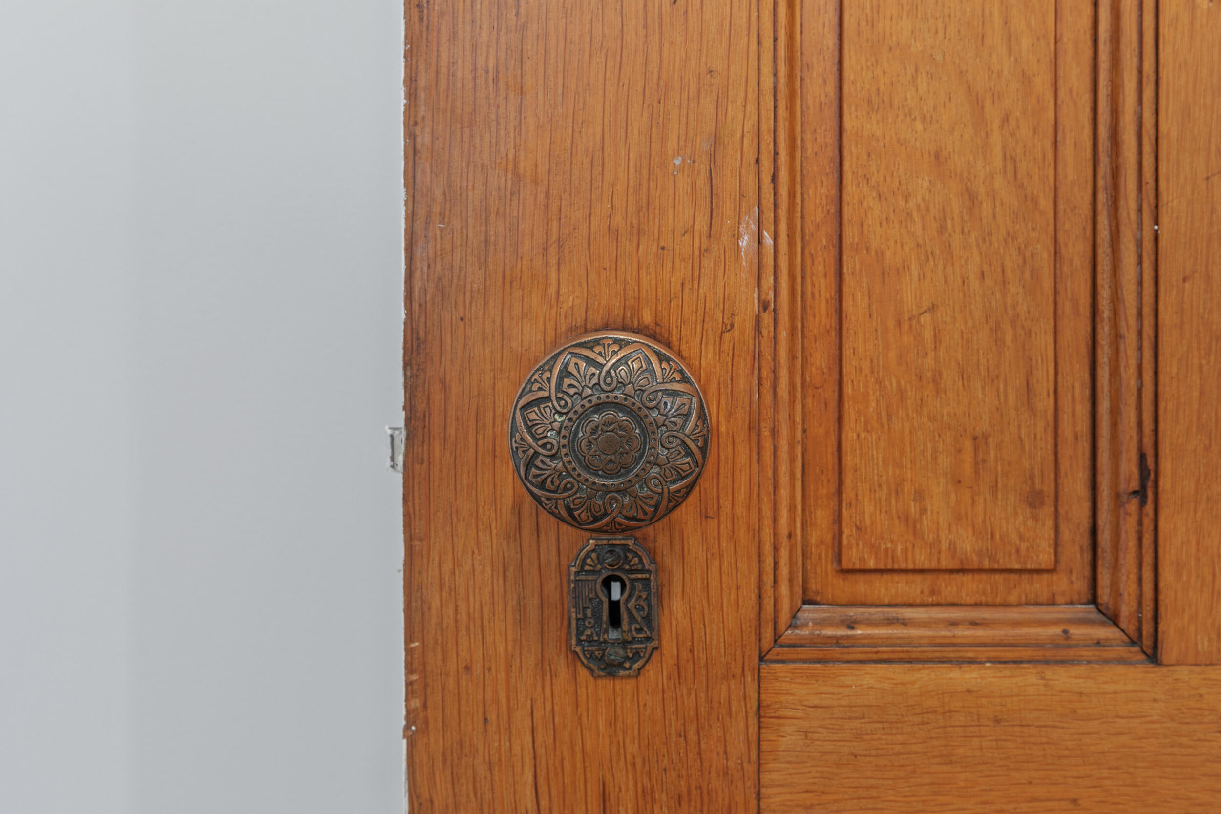 Wooden paneled door with ornate antique brass doorknob and keyhole