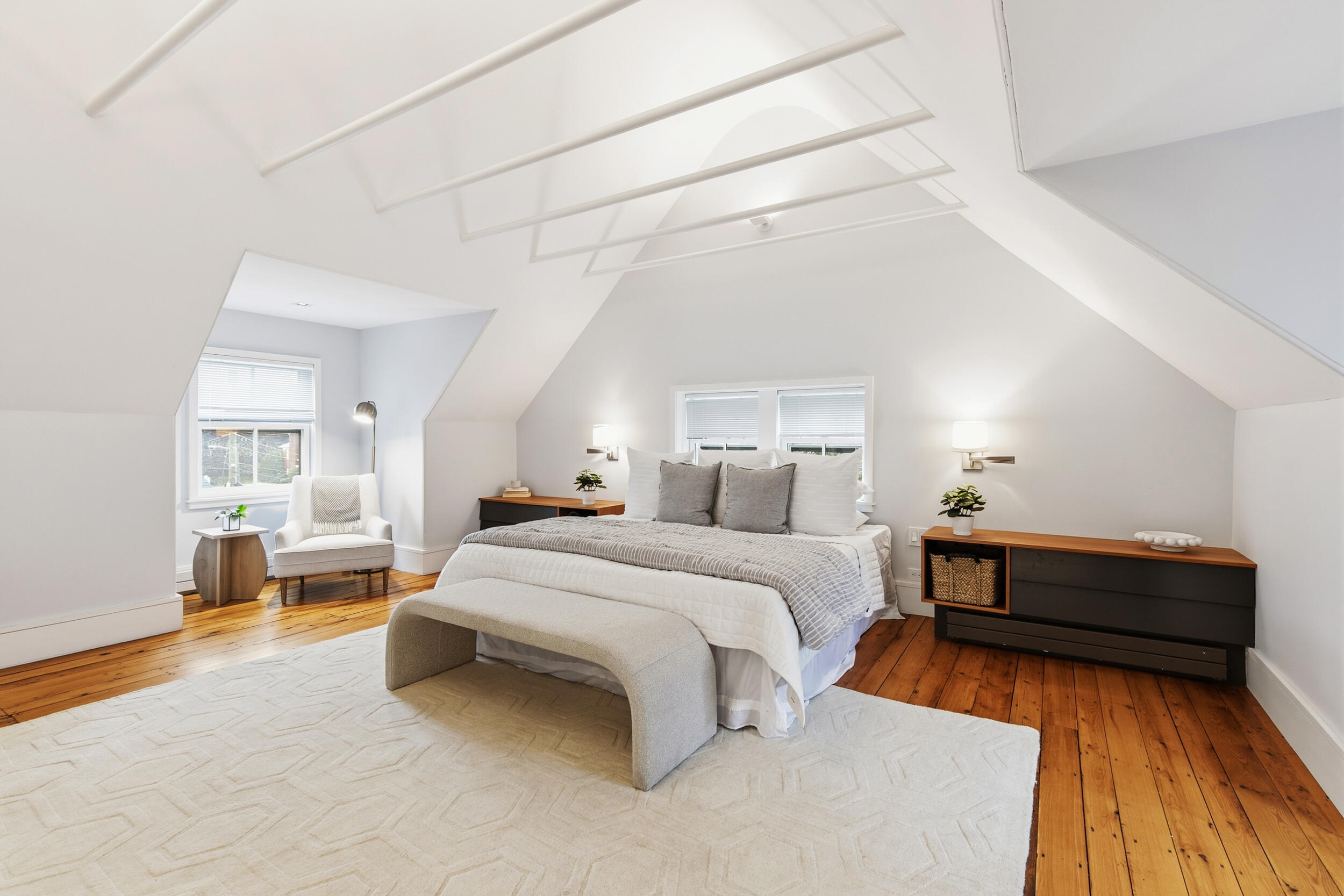 Attic bedroom with a large bed, sloped ceiling, and warm wood floors.