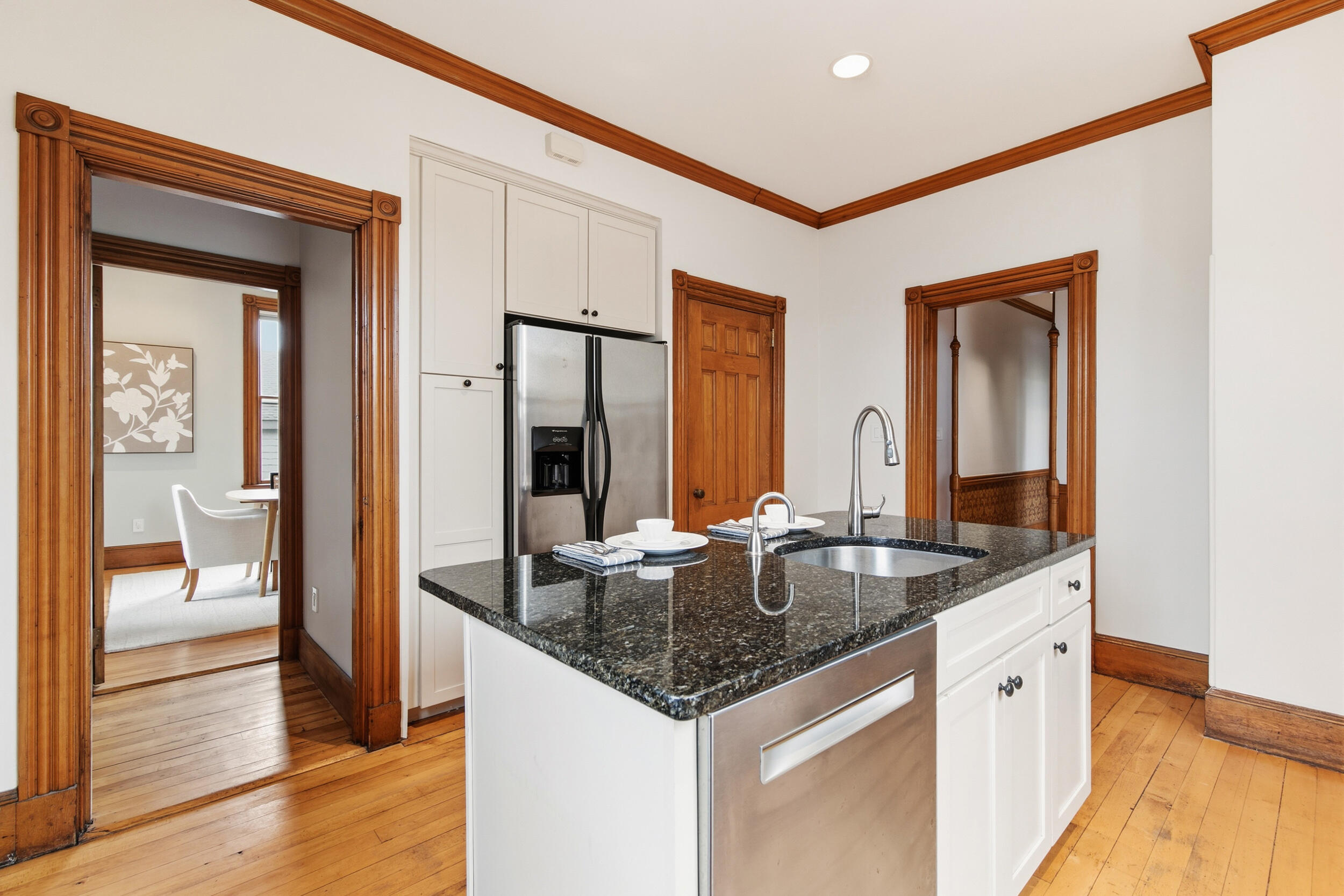 Kitchen with a granite island, stainless steel appliances, and ornate wood trim.