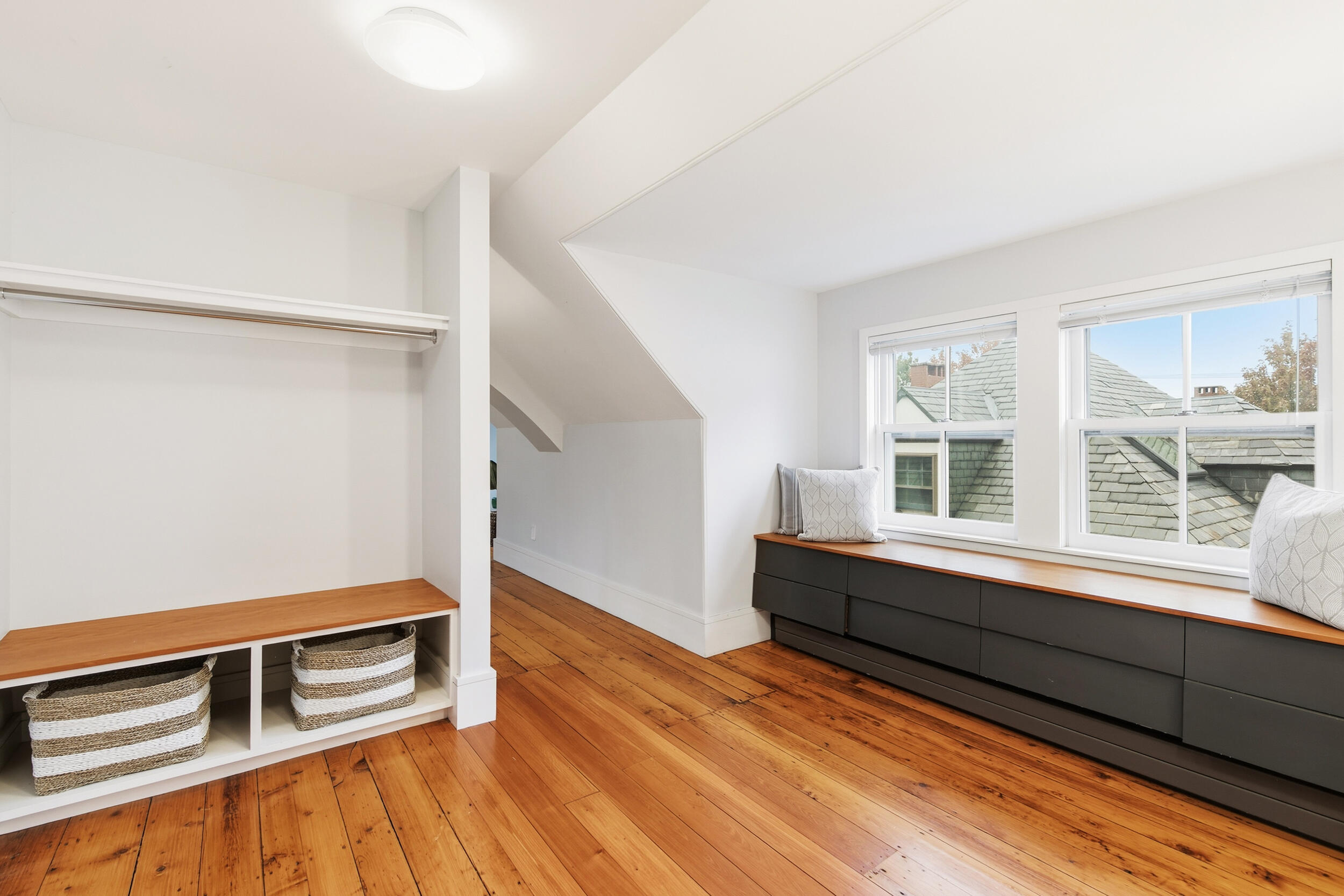 Bright room with built-in closet storage, window bench, and warm wood floors.