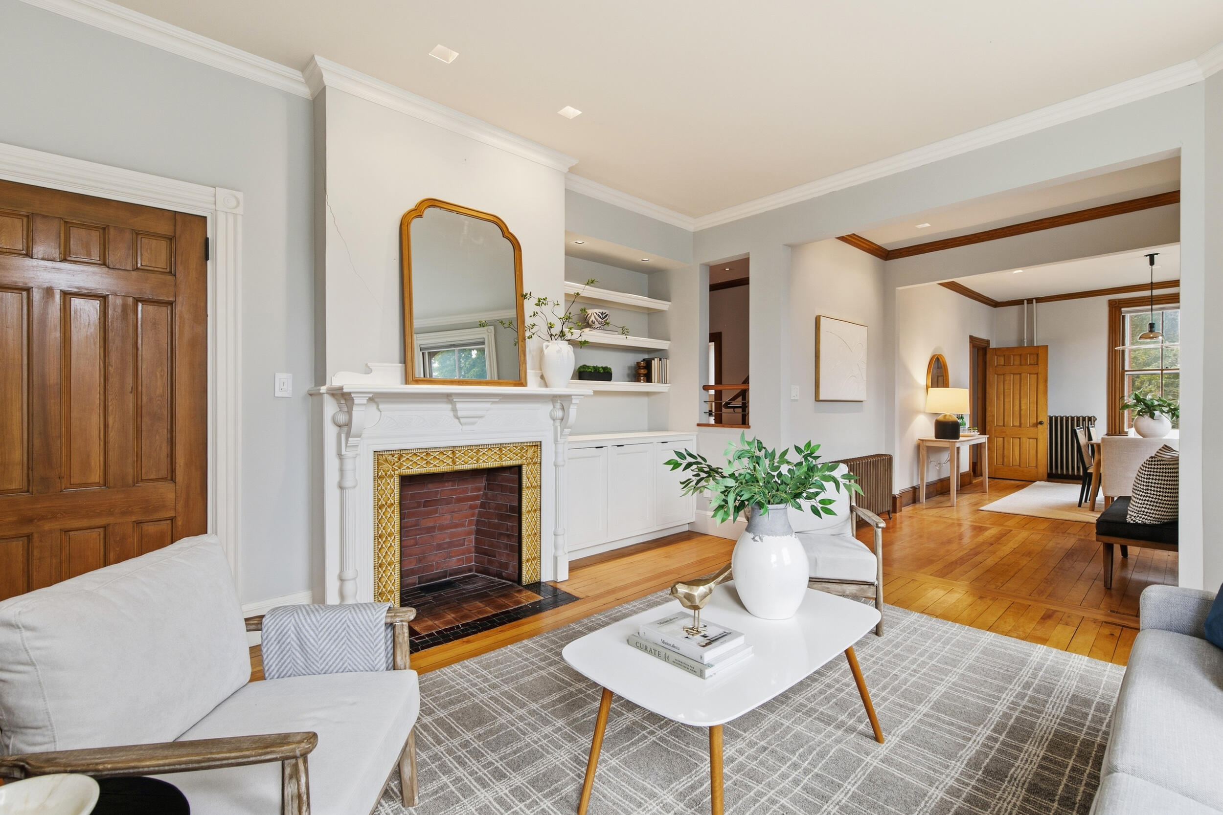 Living room with ornate tiled fireplace, built-in shelves, and hardwood floors.
