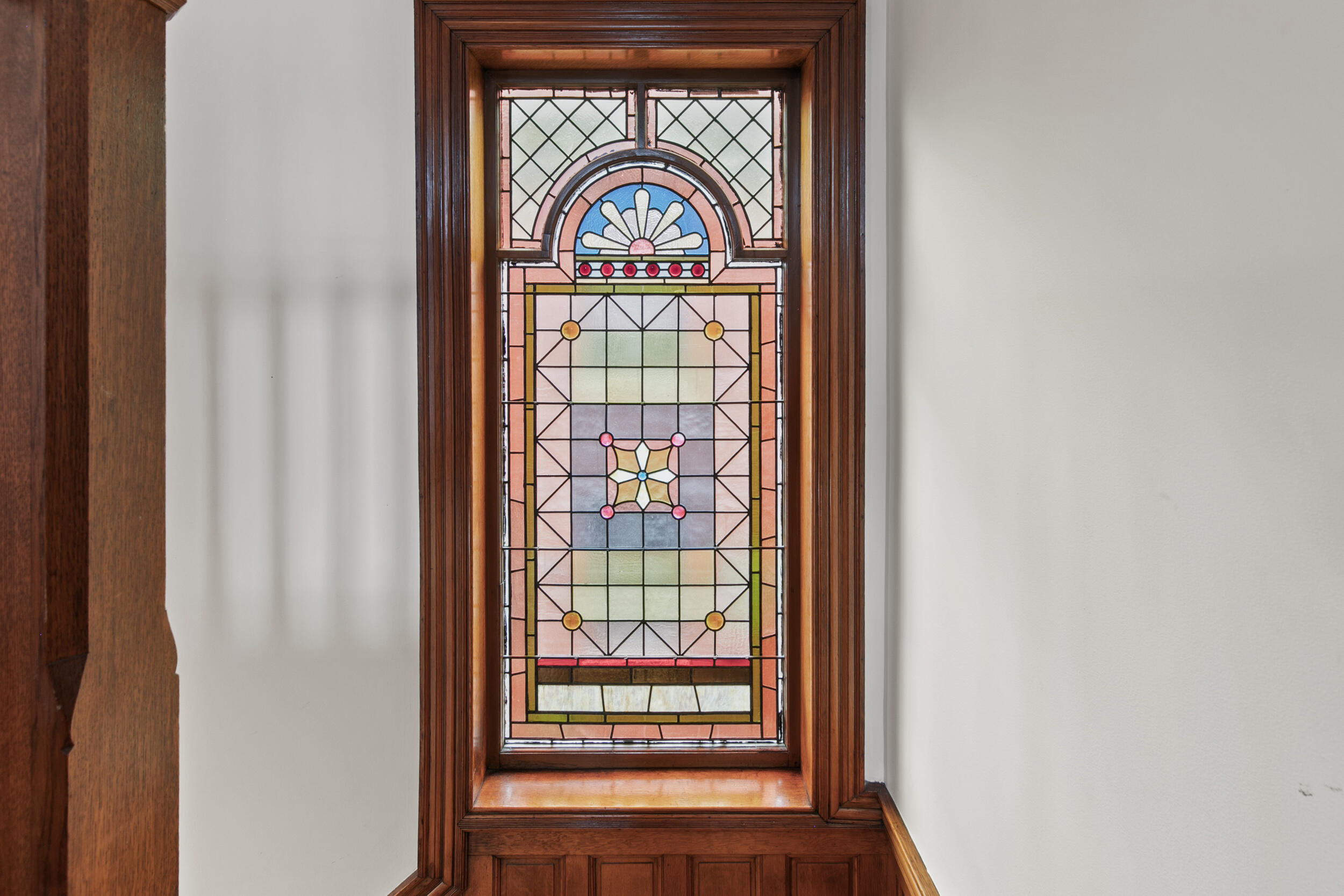 Stained-glass window set in an ornate dark wood frame and paneling.