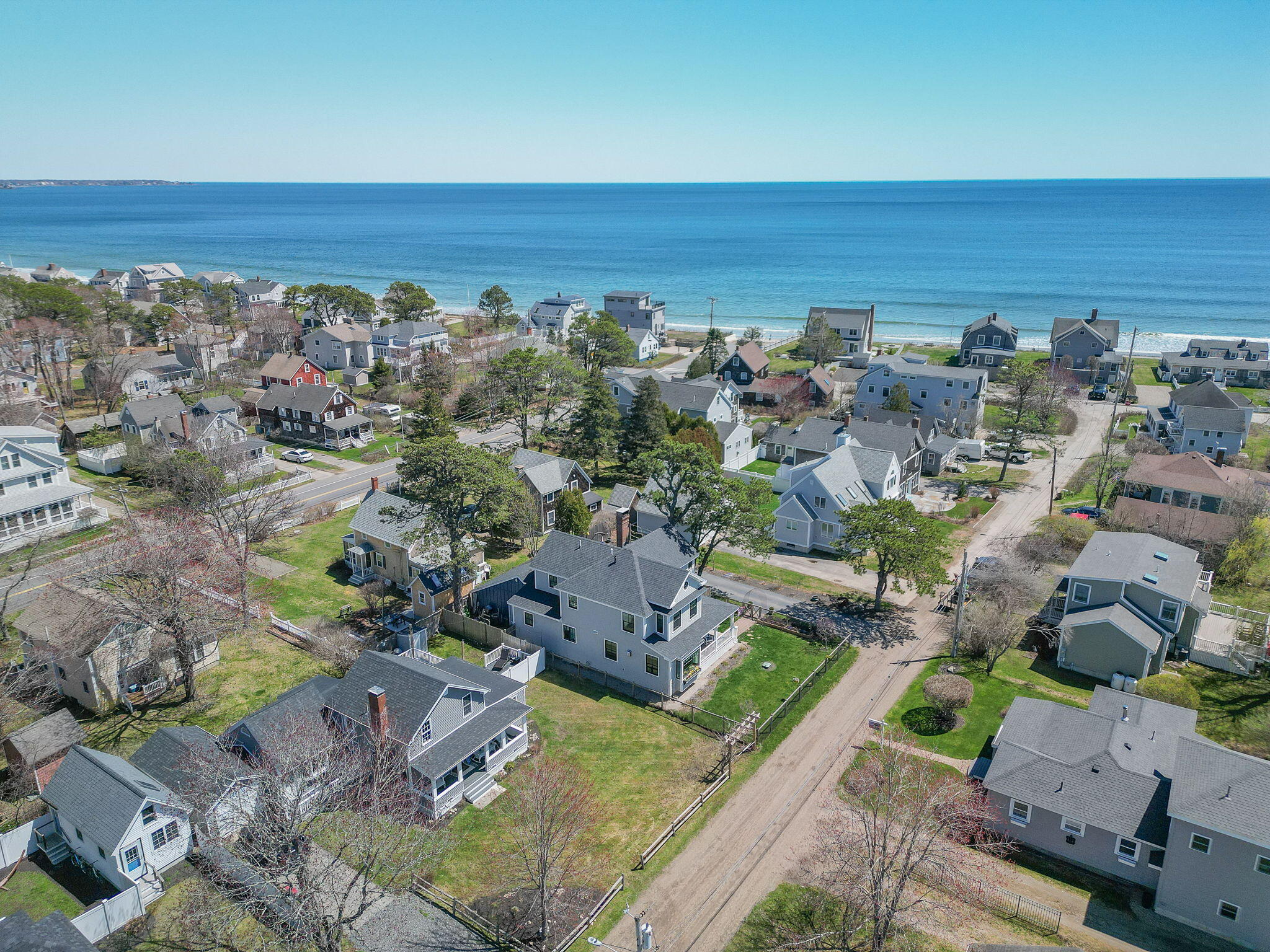 Aerial view of coastal homes and roads with the ocean beyond.