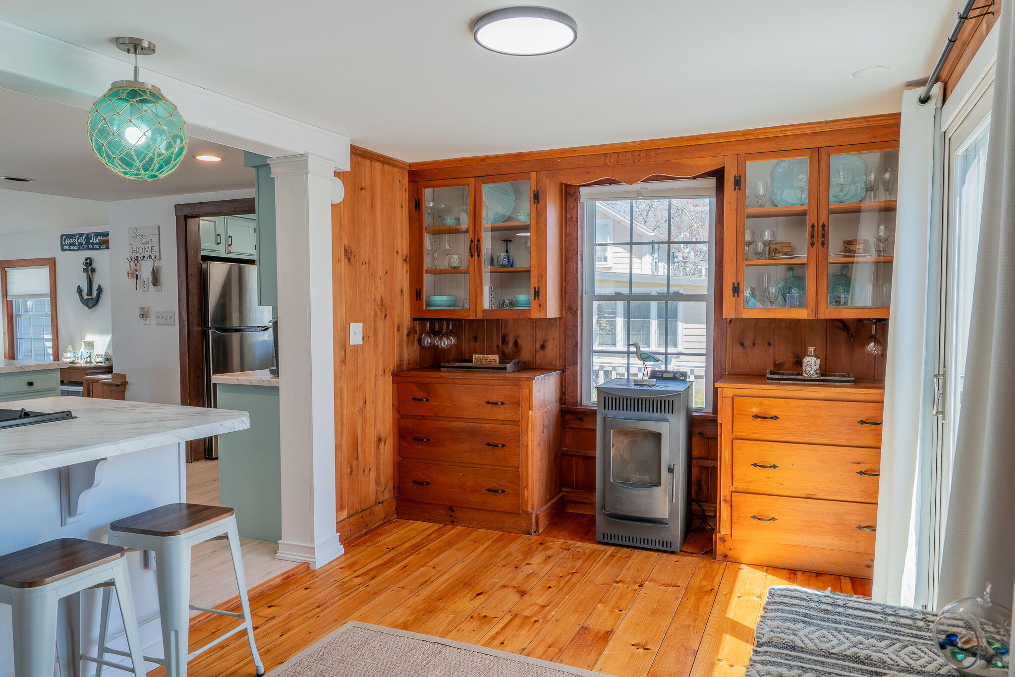 Kitchen with pine floors, glass-front built-in cabinets, and a freestanding wood stove.