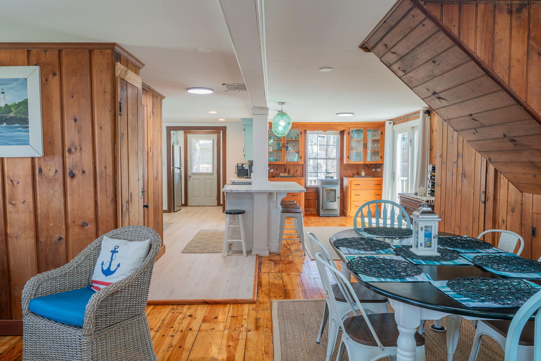 Open kitchen and dining area with a central island, wood cabinetry, and a staircase overhead.