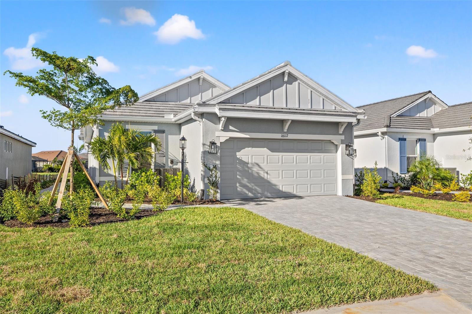 Gray single-story home with a two-car garage, landscaped yard, and paved driveway.