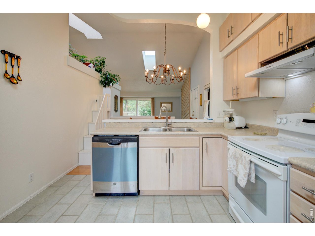 Kitchen with light wood cabinets, a double-basin sink, and stainless-steel dishwasher.