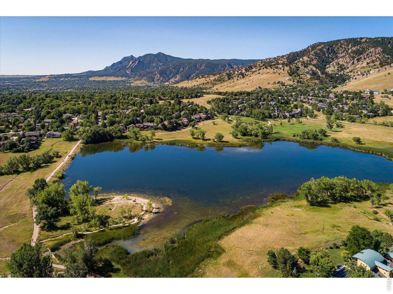 Aerial view of a neighborhood lake, walking paths, and mountain foothills.