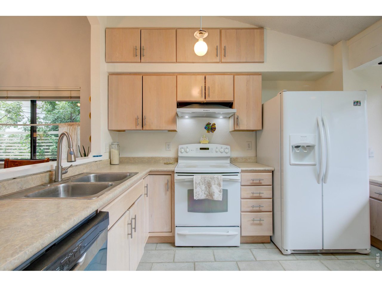 Kitchen with light wood cabinets, double-basin sink, white range, and side-by-side refrigerator.