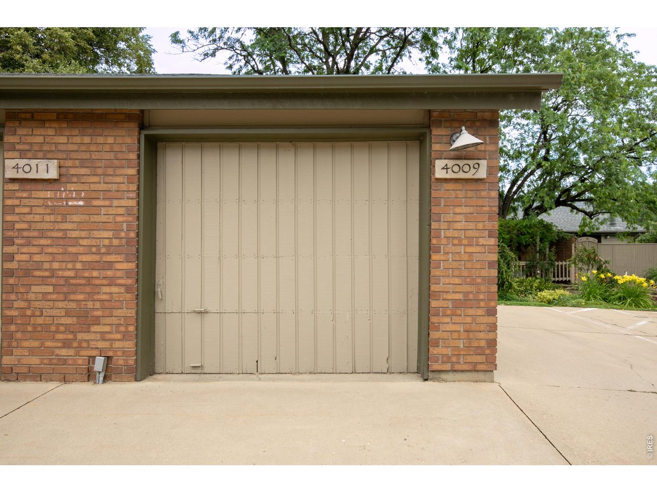 Brick garage with beige door, 4009 address plaque, and concrete driveway.