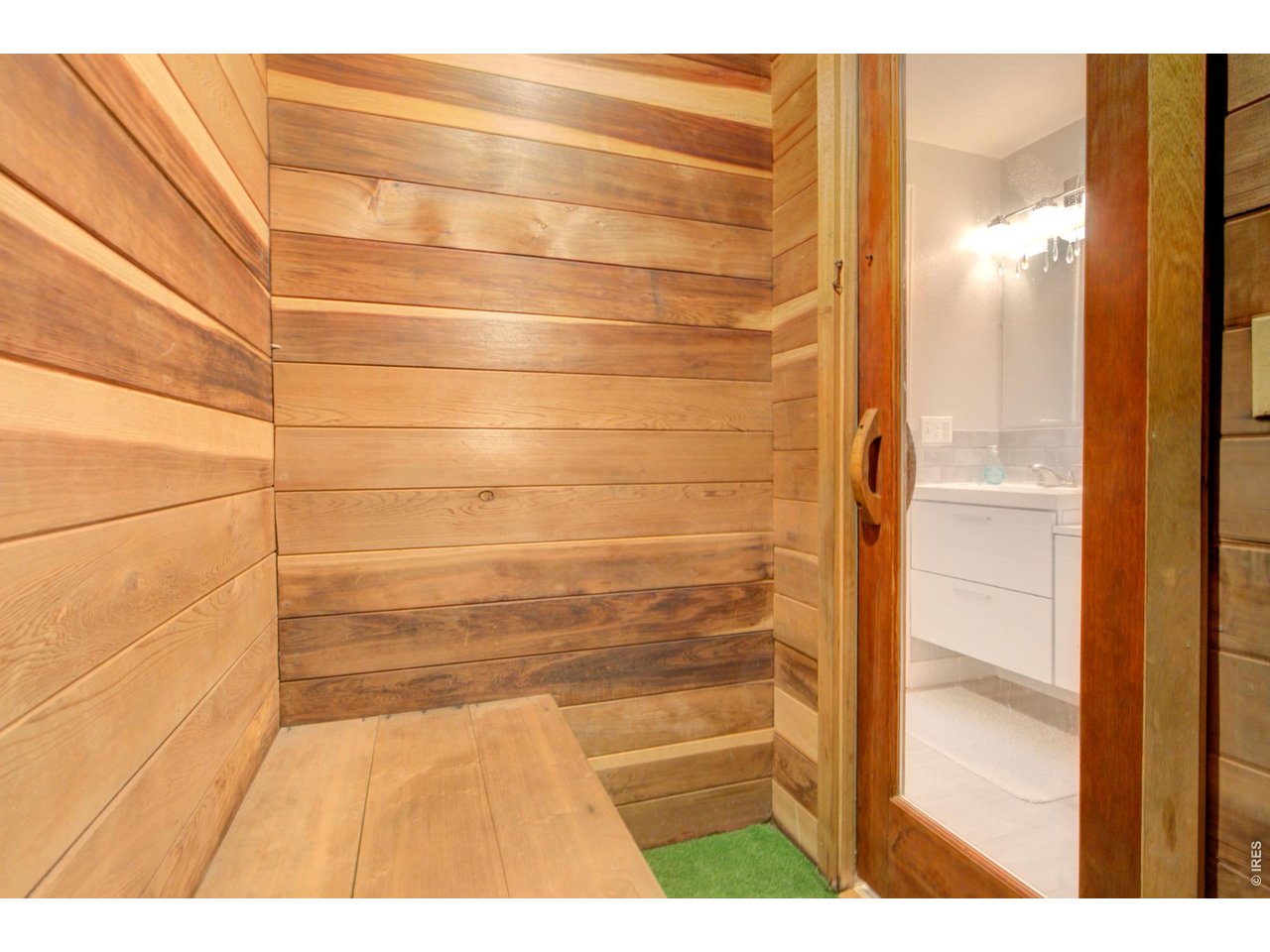 Wood-paneled sauna with a built-in bench beside an adjoining bathroom.