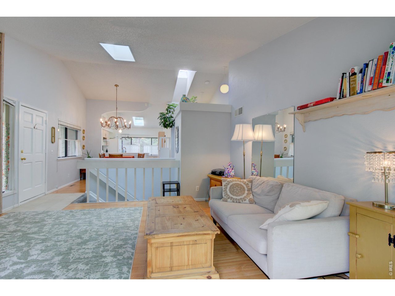Living room with a light sectional, wooden coffee table, patterned rug, and skylights overlooking an open dining area.
