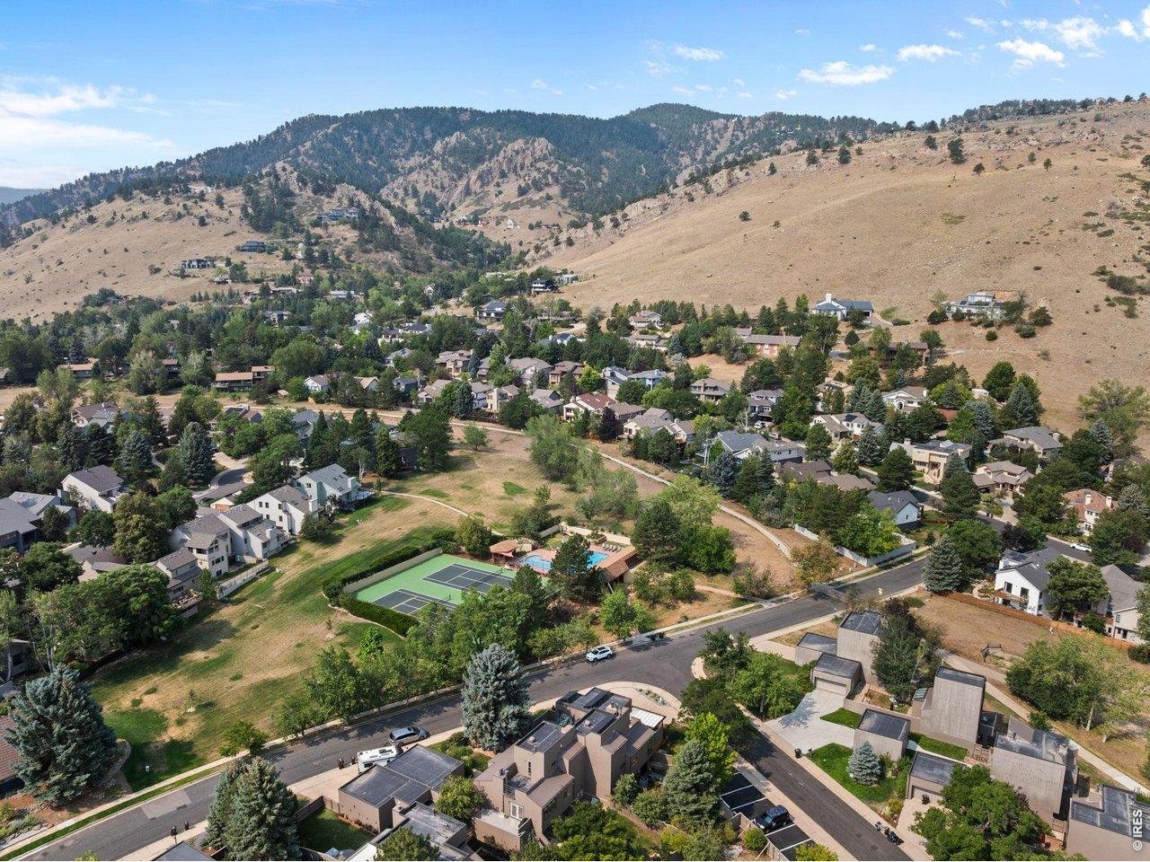 Aerial view of Boulder neighborhood below dry foothills, with tennis court and swimming pool.