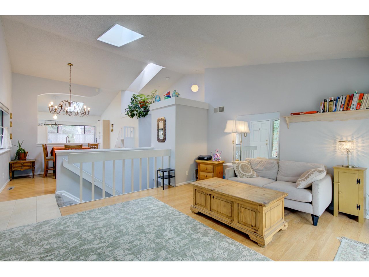 Open-plan living room with a white sofa, rustic wood coffee table, and skylights.