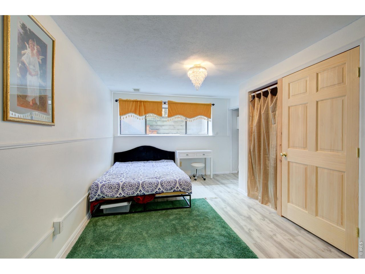 Bedroom with a patterned bedspread, green carpet, and large wooden closet door.