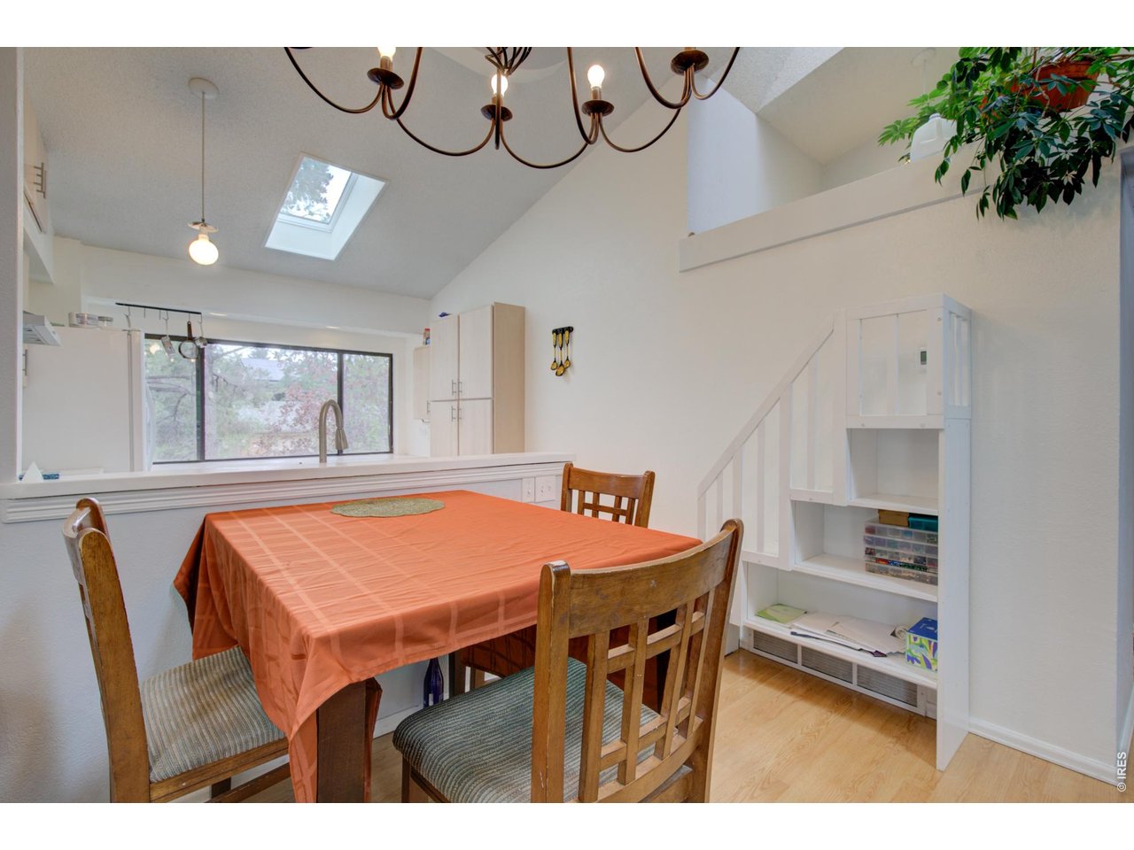 Dining area with a wooden table, orange tablecloth, vaulted ceiling, and skylight.