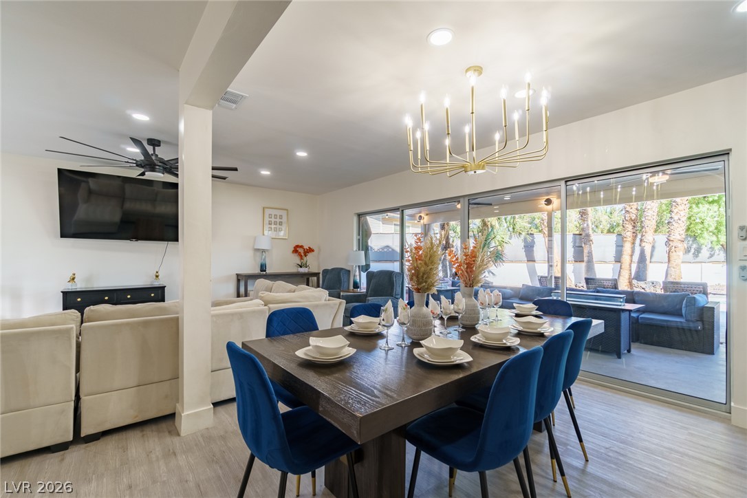 Dining and living area with blue chairs and wide sliding glass doors opening onto a patio.