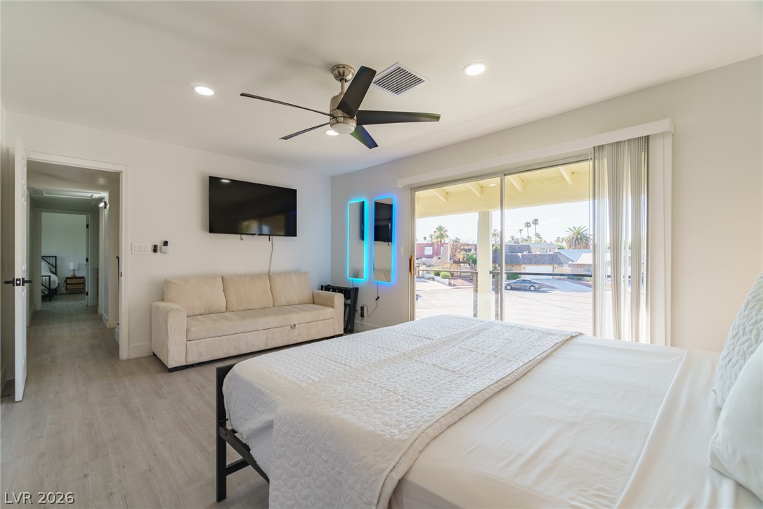 Bedroom with a large white bed, beige sofa, and sliding glass doors to a covered patio.
