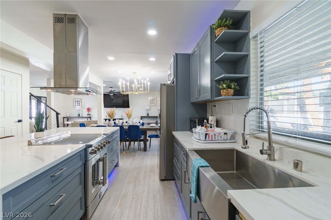 Renovated kitchen with blue-gray cabinets, a stainless steel range, and a deep farmhouse sink.