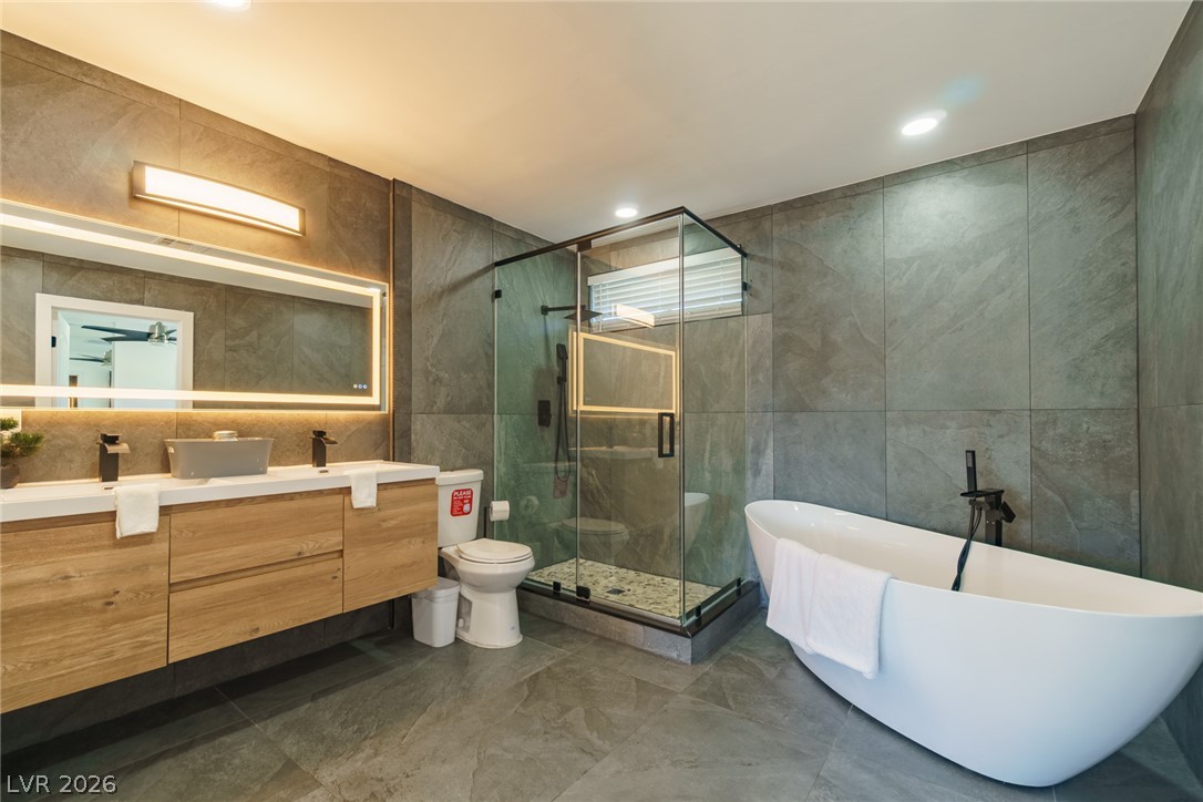 Modern bathroom with a wood floating vanity, glass shower, and freestanding white tub.