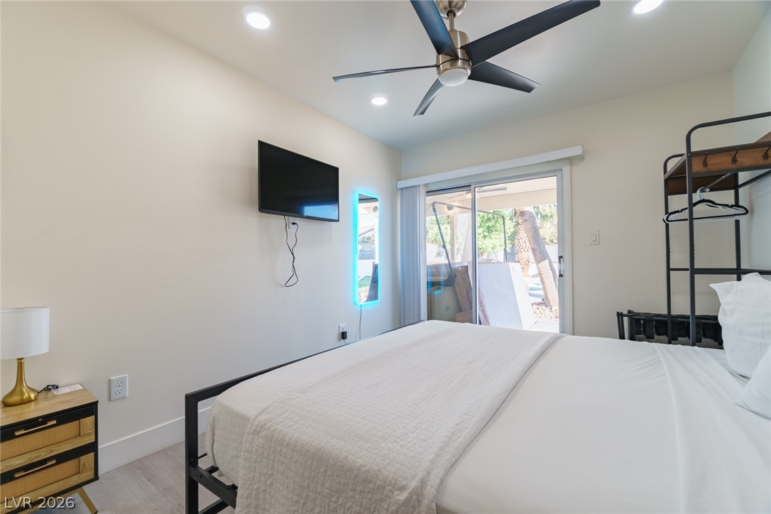 Bedroom with a white bed, wall-mounted television, and sliding glass doors overlooking the outdoor area.