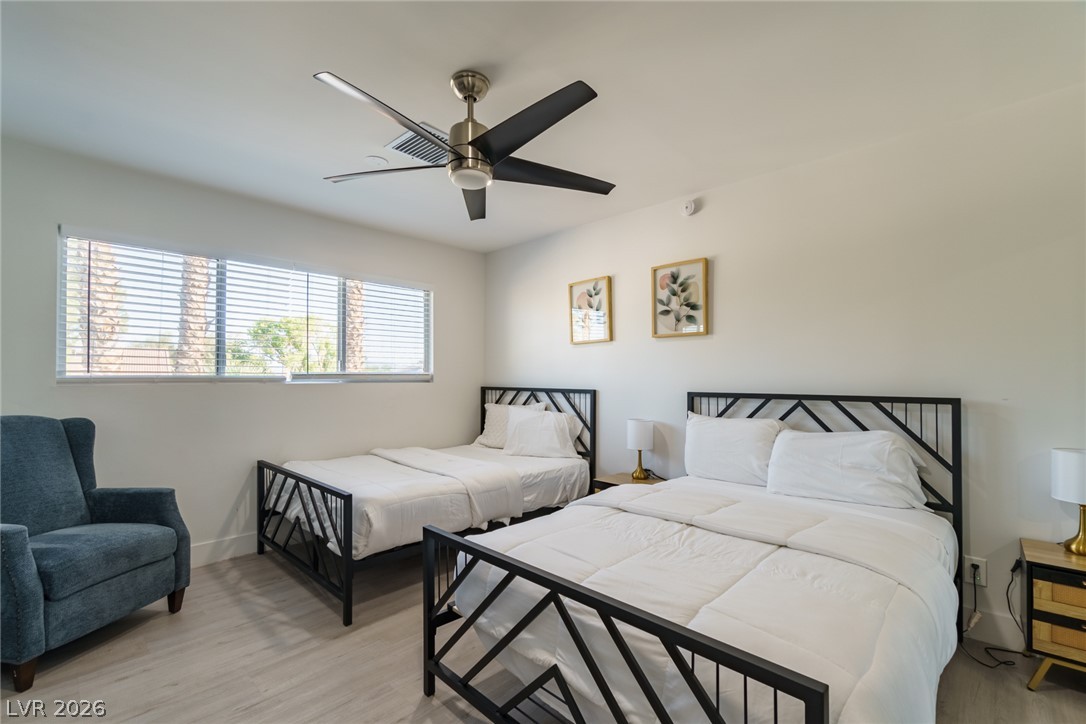 Bedroom with two black metal-frame beds, white bedding, and a blue armchair.