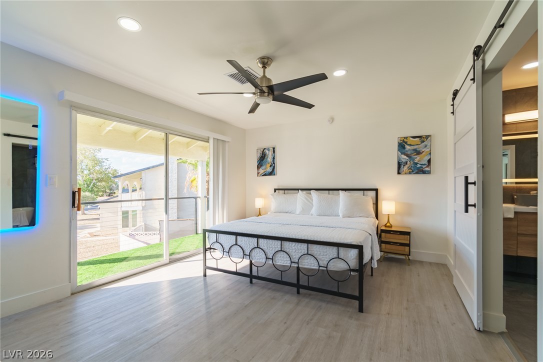 Bedroom with a black metal bed, white bedding, and sliding doors opening to a patio.