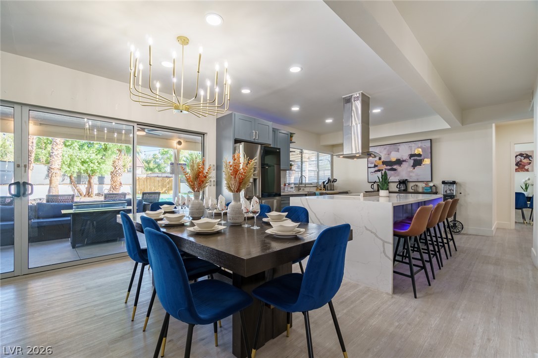 Open-plan kitchen and dining area with a white island, blue chairs, and sliding glass doors to the patio.