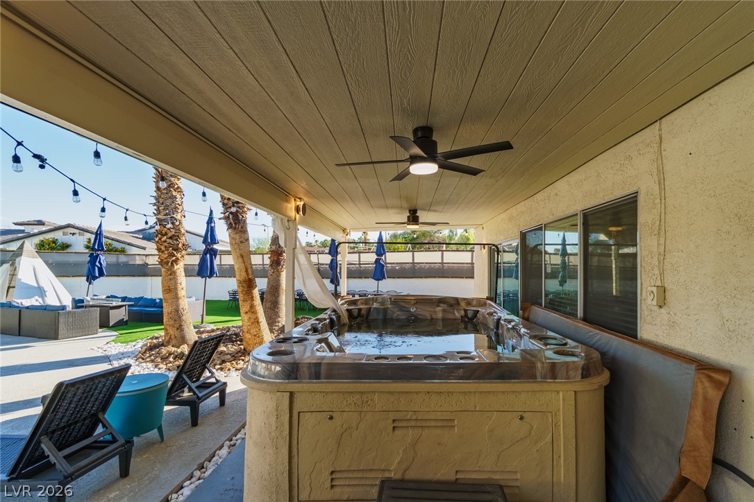 Covered patio with a large built-in hot tub, lounge chairs, and palm trees.