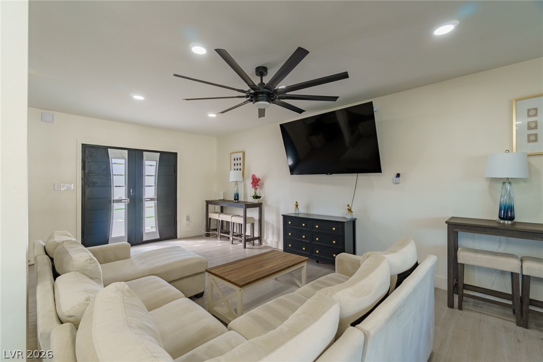 Living room with cream sectional sofas, a wood coffee table, and dark double doors with glass panels.