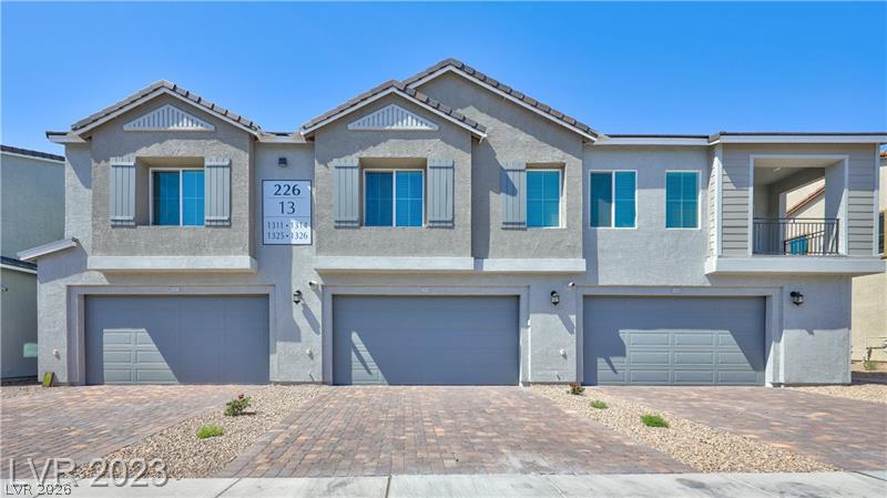Attached two-story homes with three garage doors, blue-tinted windows, and a paved driveway.