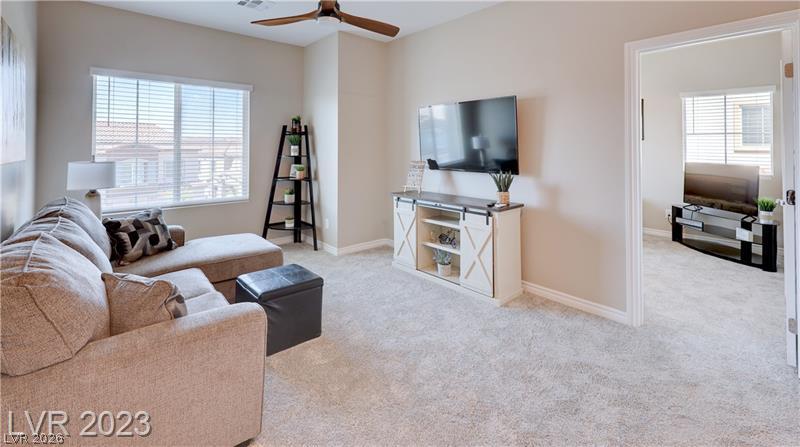 Furnished living room with beige sectional, wall-mounted TV, and a doorway to another room.