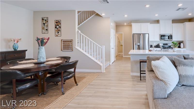 Open-plan dining room and kitchen with a staircase, island, and gray sofa.