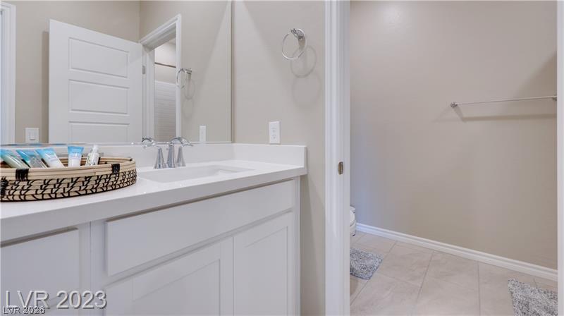 Bathroom vanity with a large mirror and woven tray of toiletries beside an open doorway.