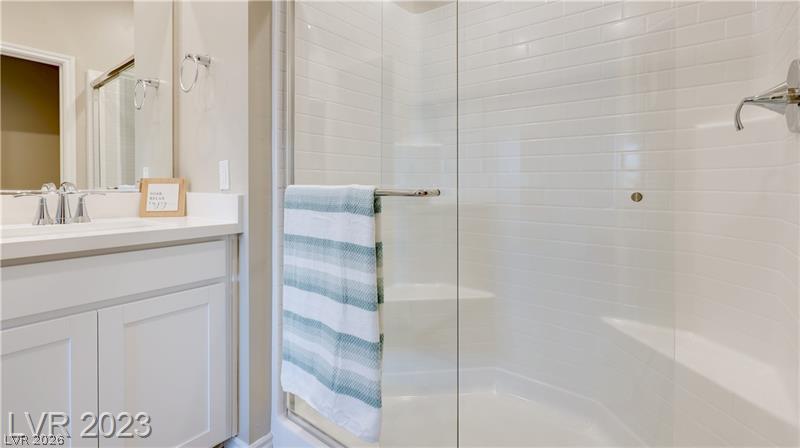 Bathroom with a white vanity and glass-enclosed tub and shower, accented by a striped towel.