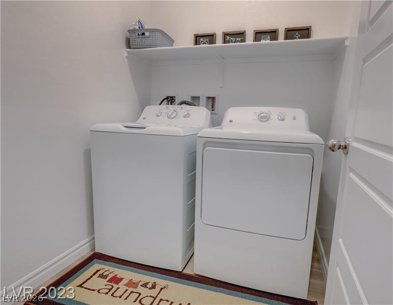 Laundry room with a white washer and dryer, overhead shelf, and laundry-themed floor mat.