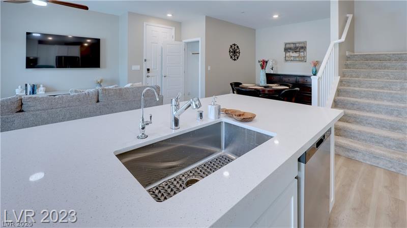 Open-plan kitchen with a white quartz island and stainless-steel sink, overlooking the living and dining areas.