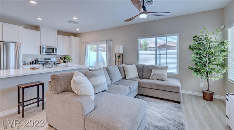 Open-plan living room with a large gray sectional sofa beside a bright white kitchen.