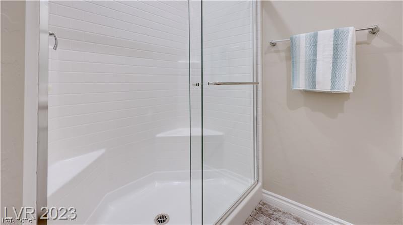 Glass-enclosed shower with white tile, a built-in corner seat, and a striped towel.
