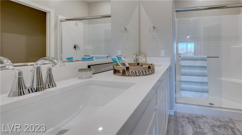 Bathroom with a white double-sink vanity and glass shower with a striped towel.