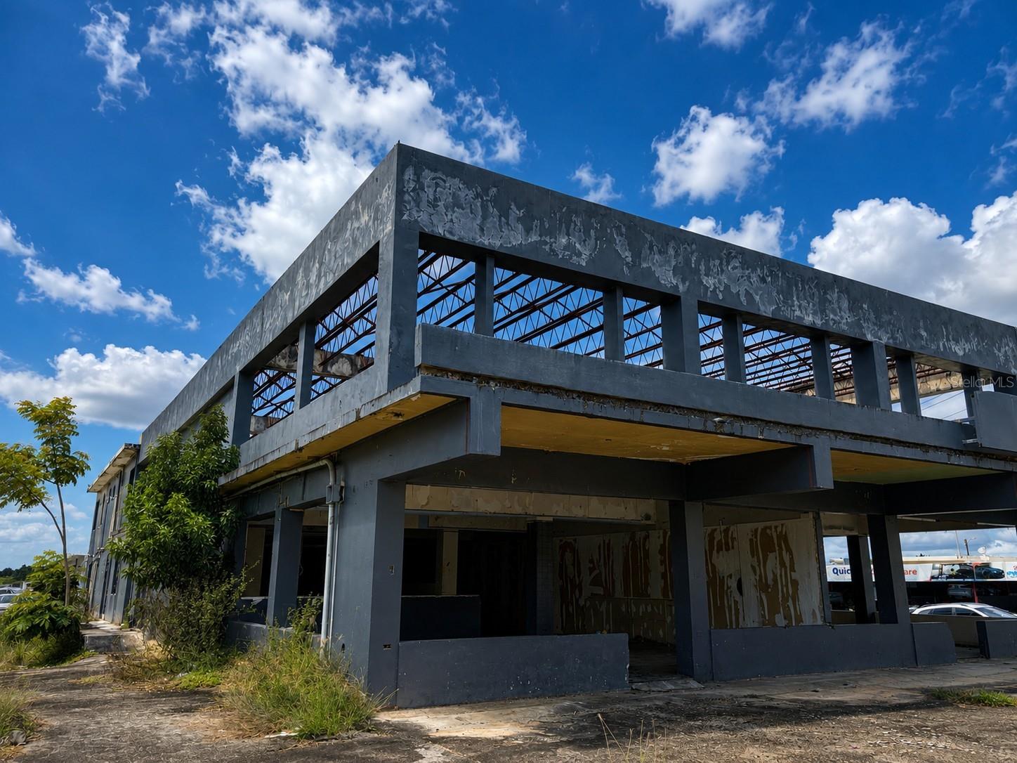 Unfinished commercial building with exposed steel roof trusses and open structural bays.