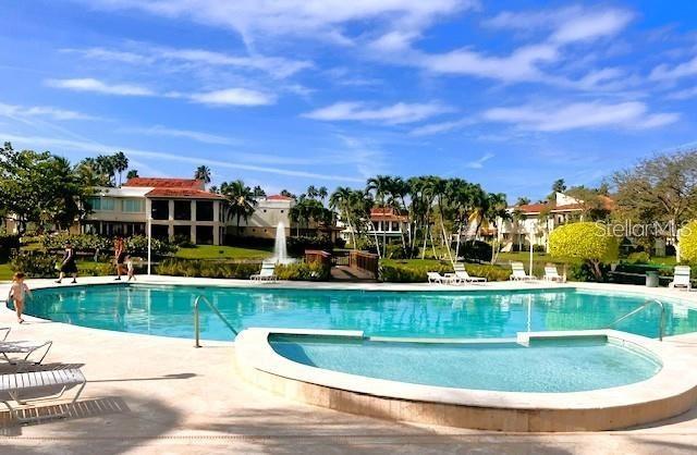 Lakeside Villas pool and curved spa, with palm trees and residences in the background.