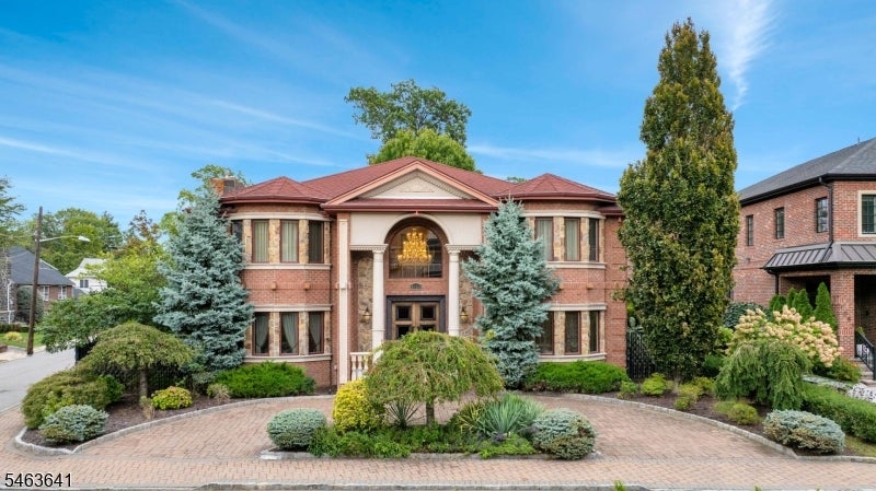 Two-story brick house with a columned entrance, landscaped gardens, and curved brick driveway.