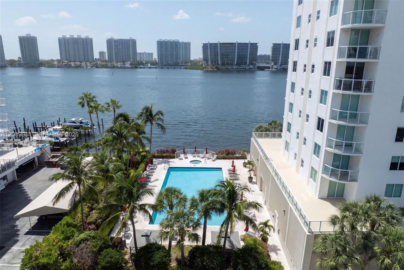 Condominium pool beside the bay, with palm trees and distant high-rises.