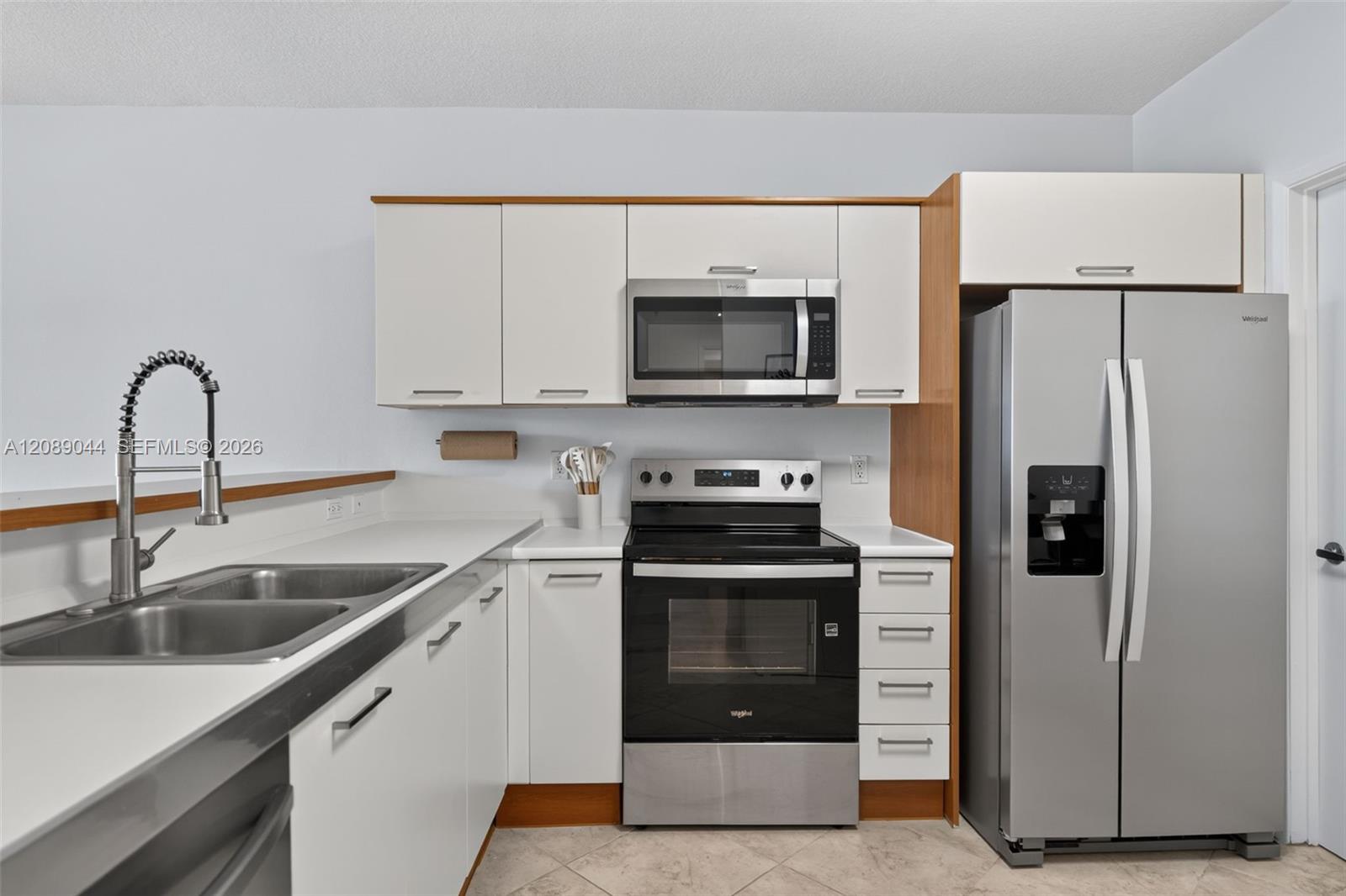 Modern kitchen with white cabinets, wood trim, and stainless steel appliances.