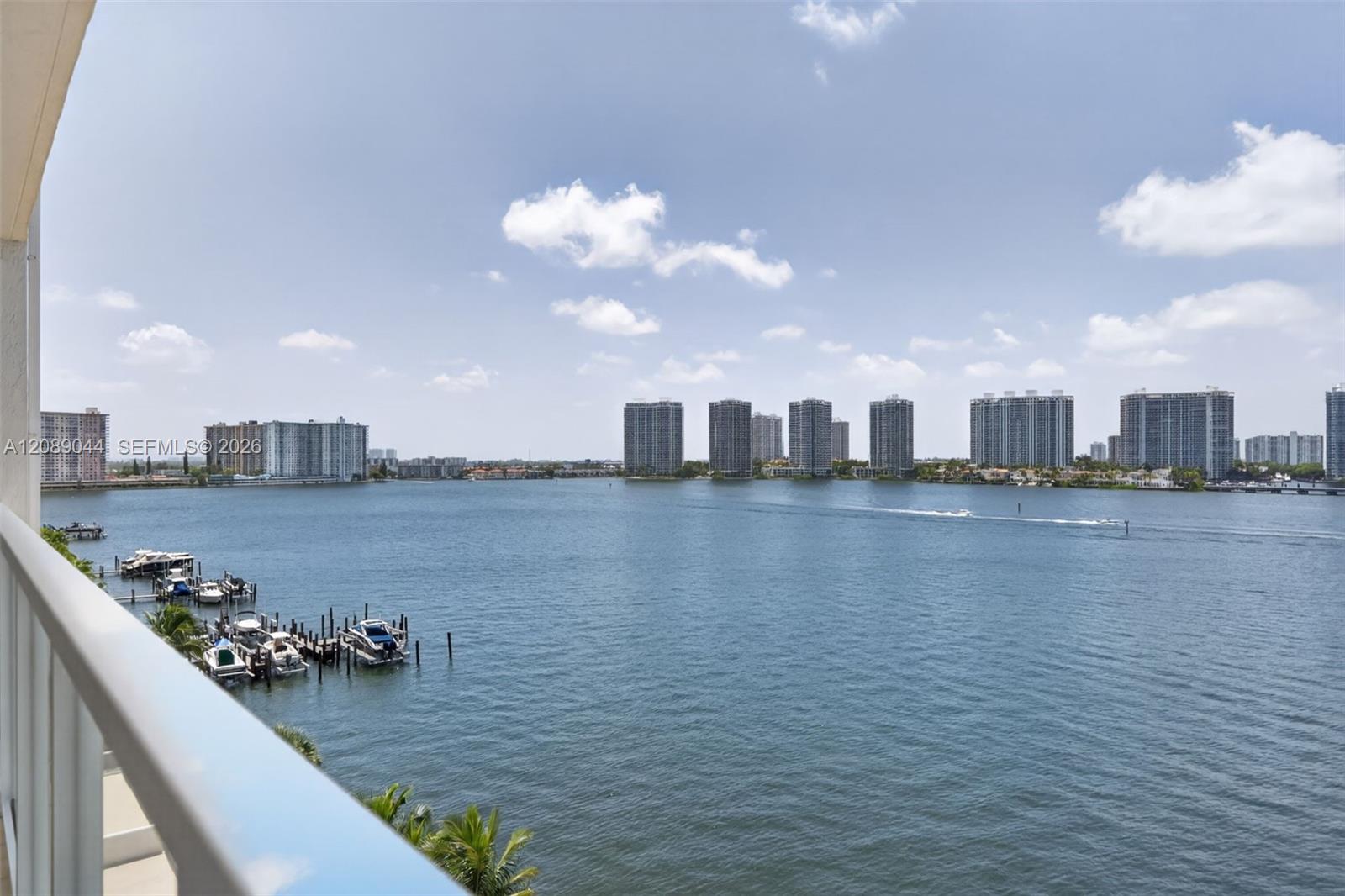 Balcony overlooking the water, with boats and high-rise buildings across the bay.