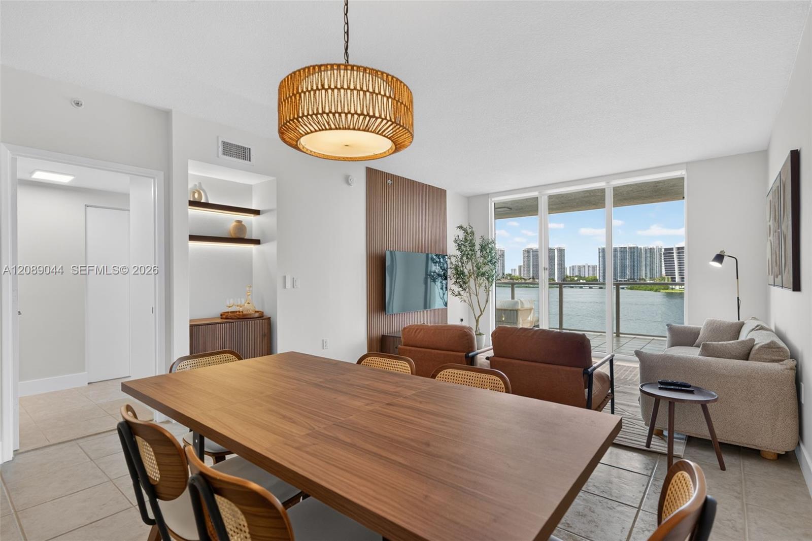Open-plan dining and living room with a wood dining table and water and skyline views.