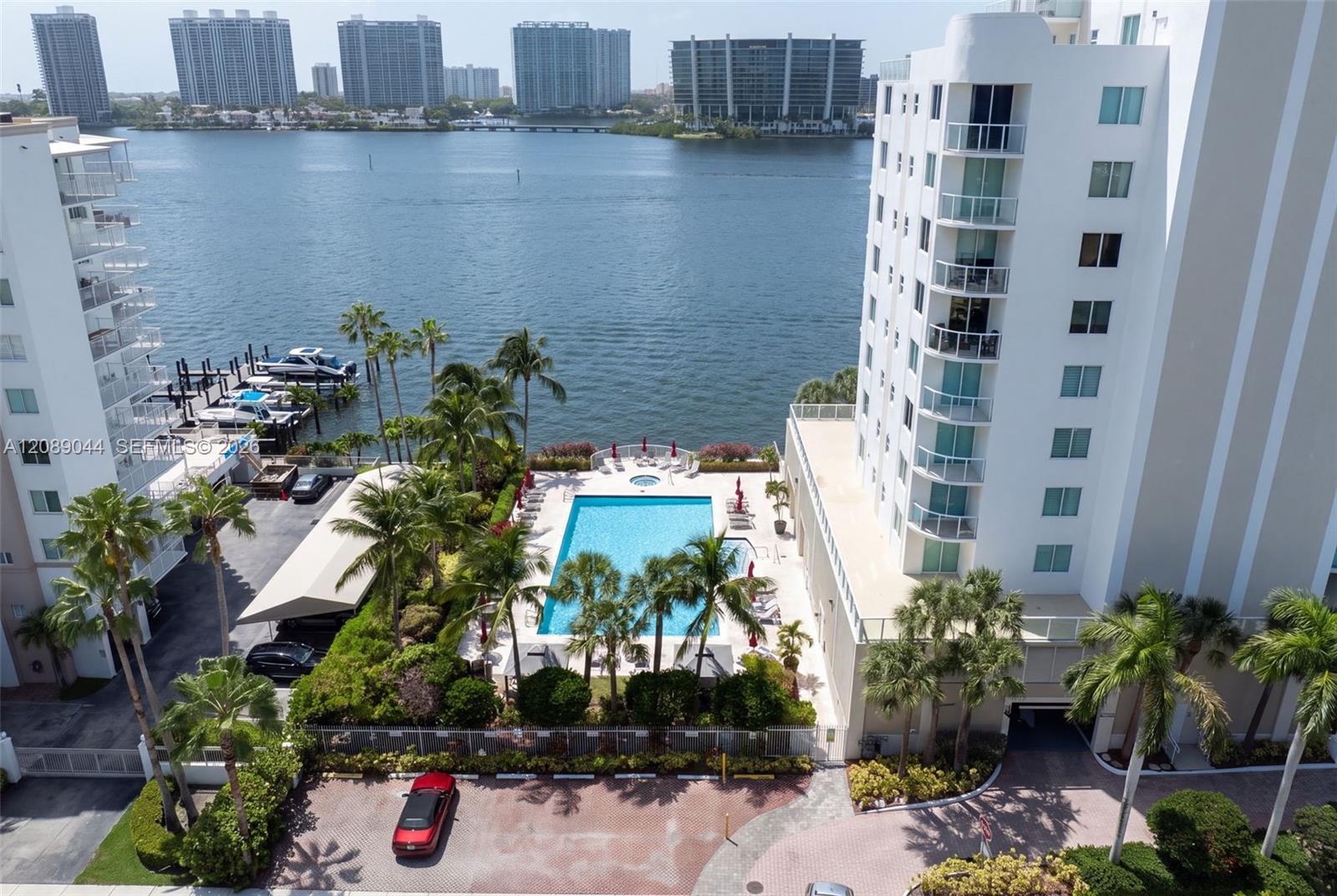 Waterfront condominium complex with a palm-lined pool and bay views between neighboring towers.